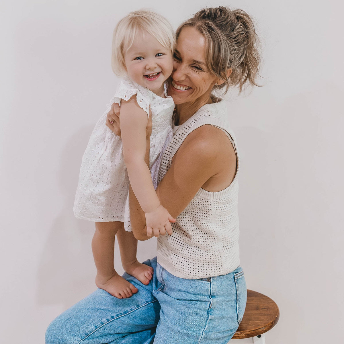 Woman holding a young child in a white eyelet dress