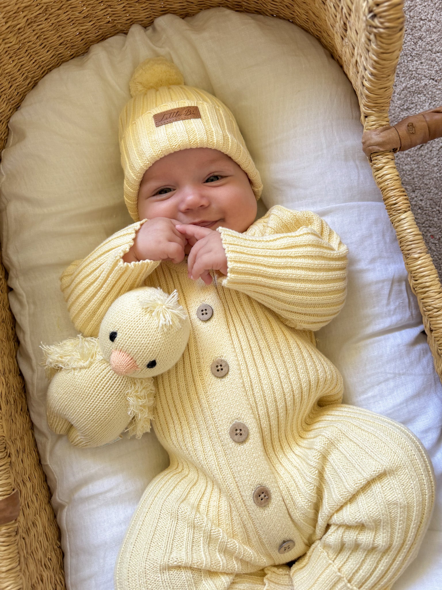 Baby in a yellow Knitted Cotton Ribbed Beanie by Little B's Retail, with a matching knitted duck toy