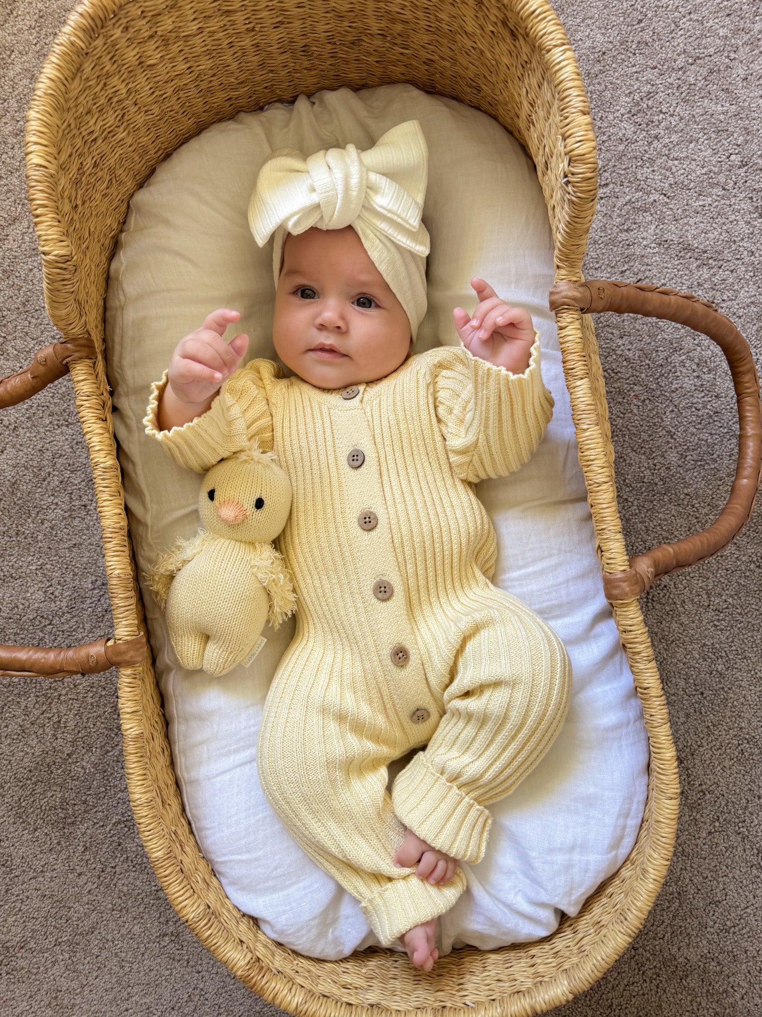 Little B's Retail Knitted Cotton Ribbed Romper - Yellow on a baby in a Moses basket with a toy chick