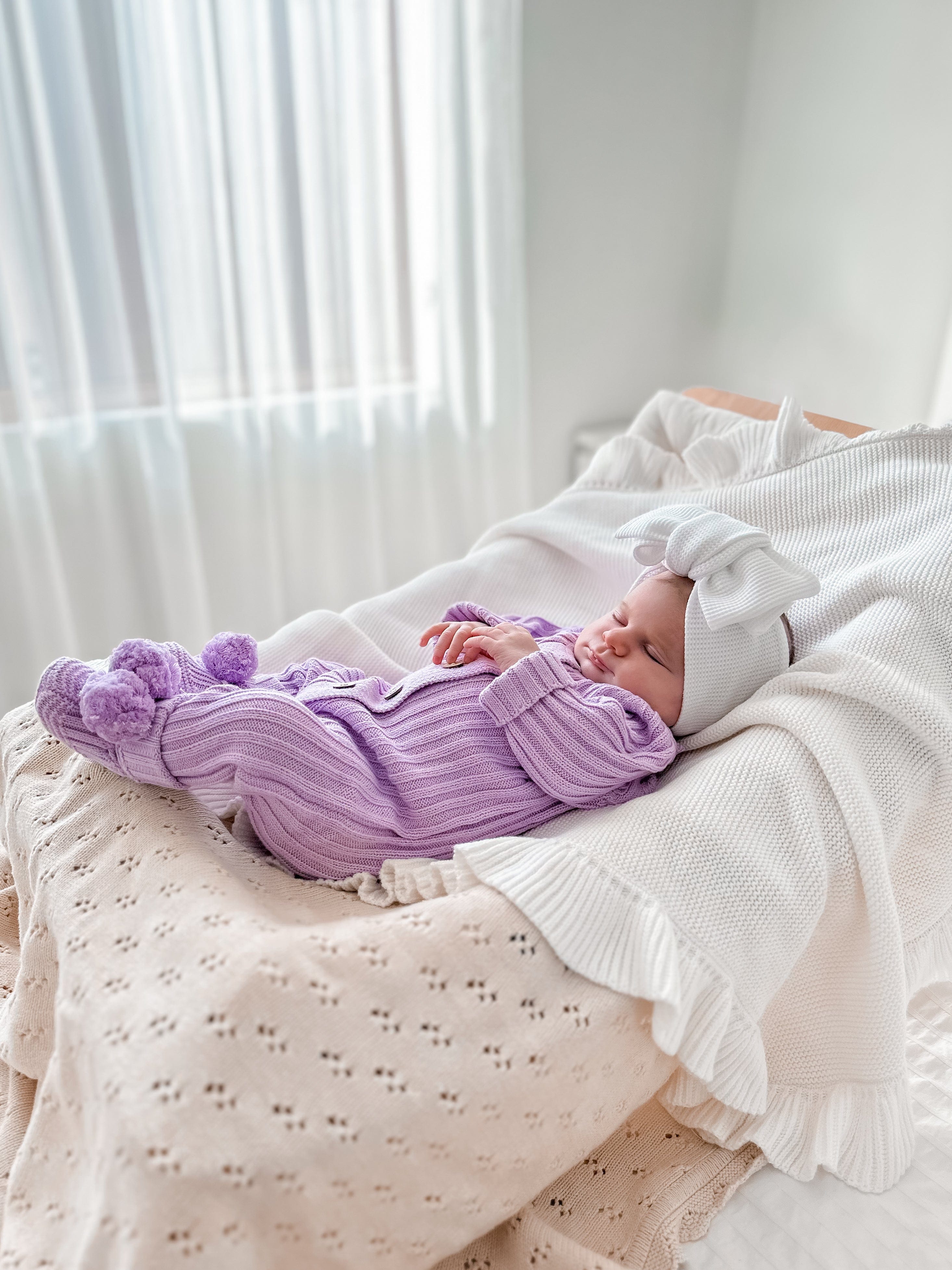 Sleeping baby in Little B's Retail Knitted Cotton Ribbed Romper in purple with pom-poms