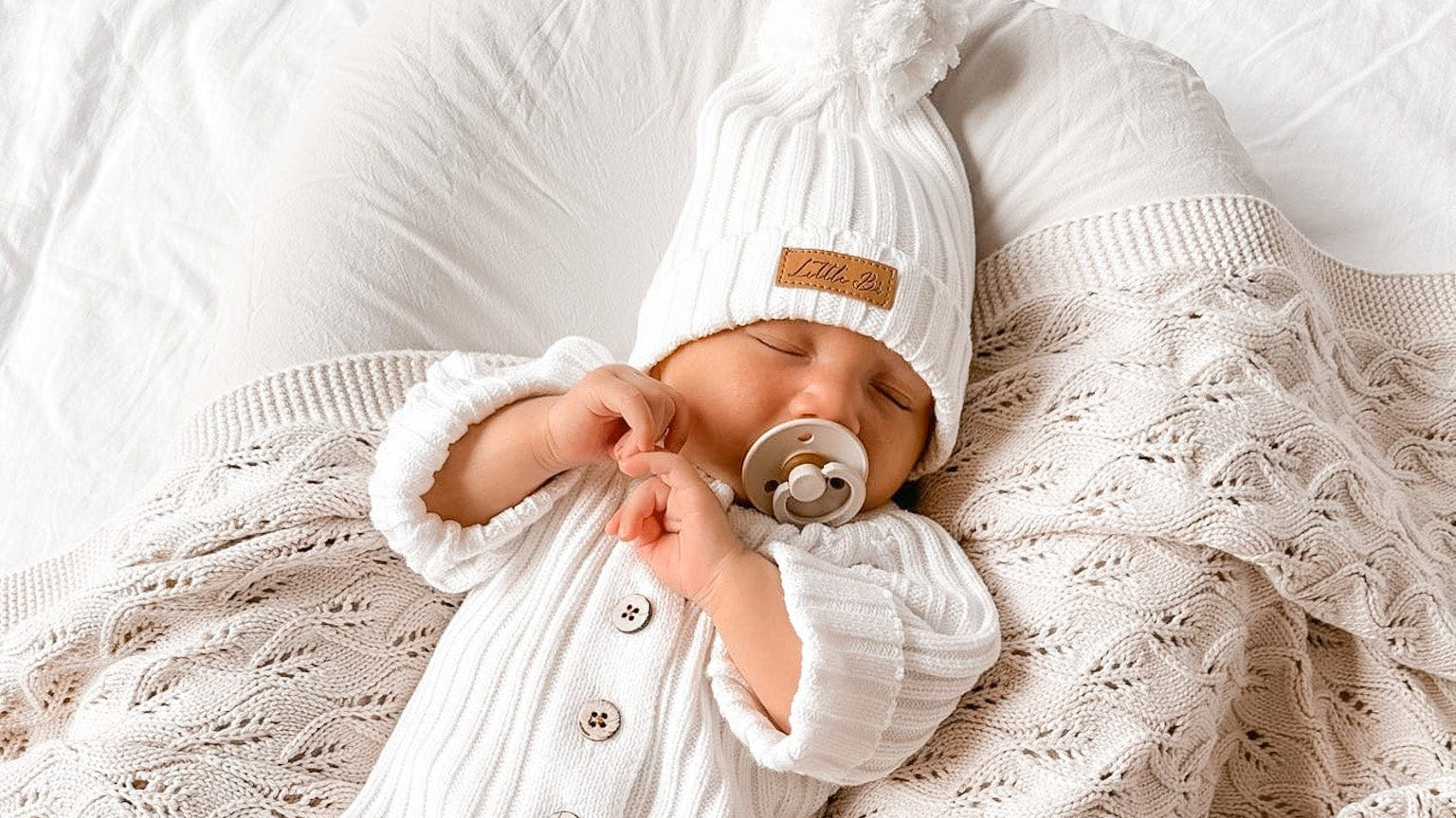 Sleeping baby wearing a Little B's Knitted Cotton Ribbed Beanie - Milk and matching outfit