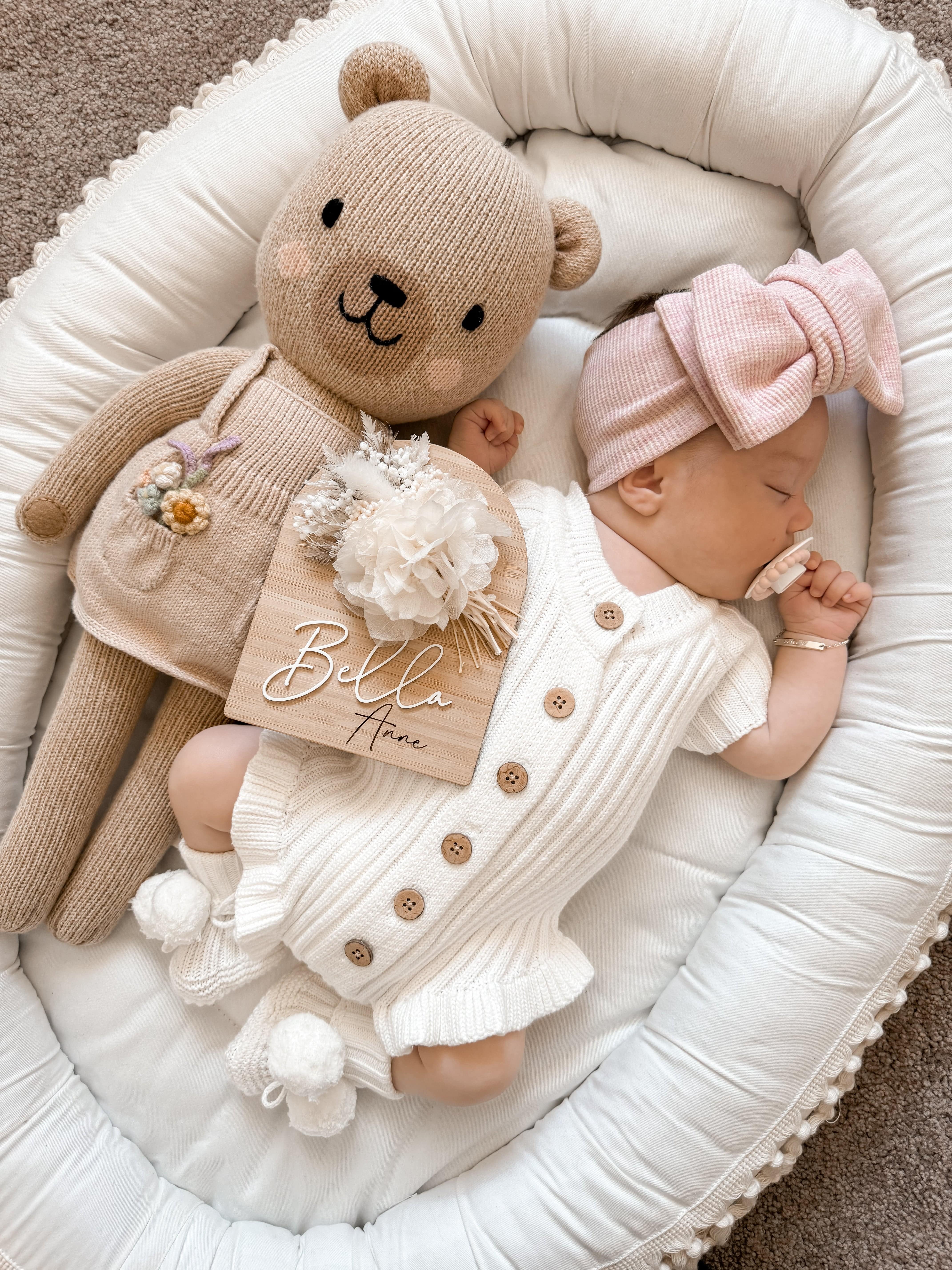 Sleeping baby in Little B's Knitted Cotton Ribbed Ruffle Romper - Milk, next to a teddy bear