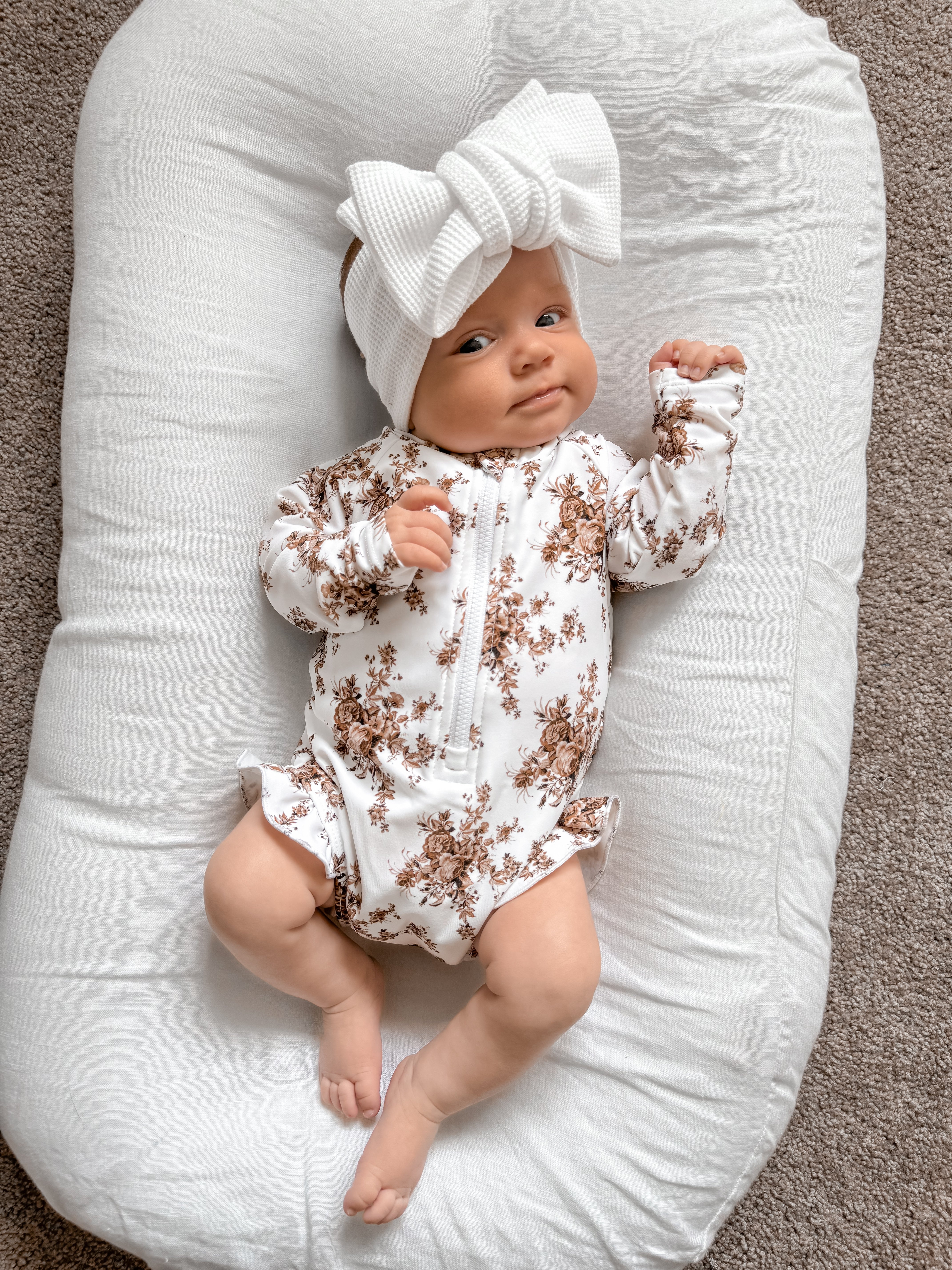 Little B's Bella Swimwear with Hat, a baby in a white floral swimsuit and white bow headband